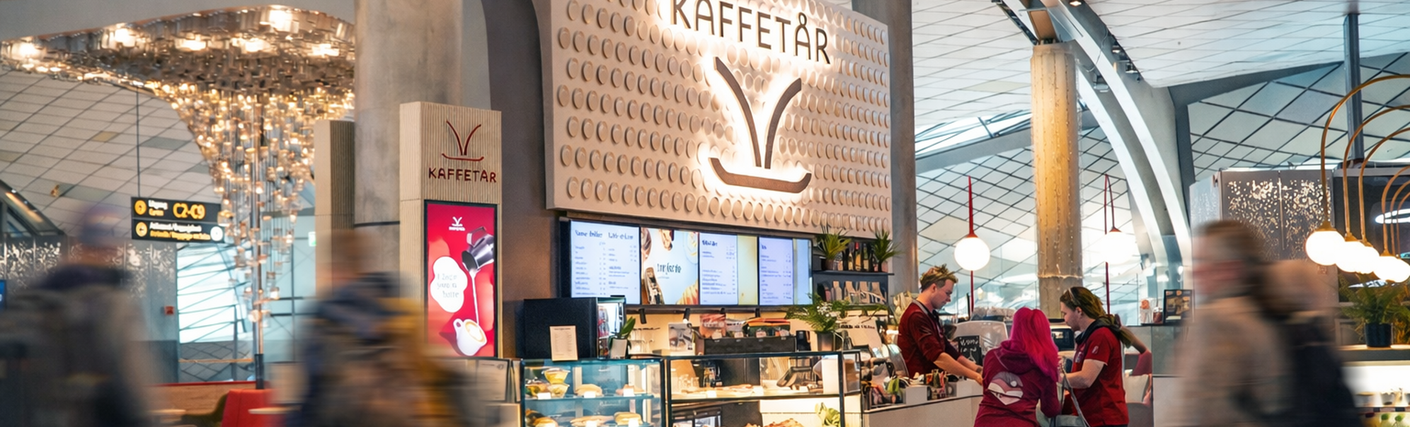 Norwegian airport lounge with seating area, decorative wall design with 'Norge', directional signs for gates and toilets, and passengers working on laptops