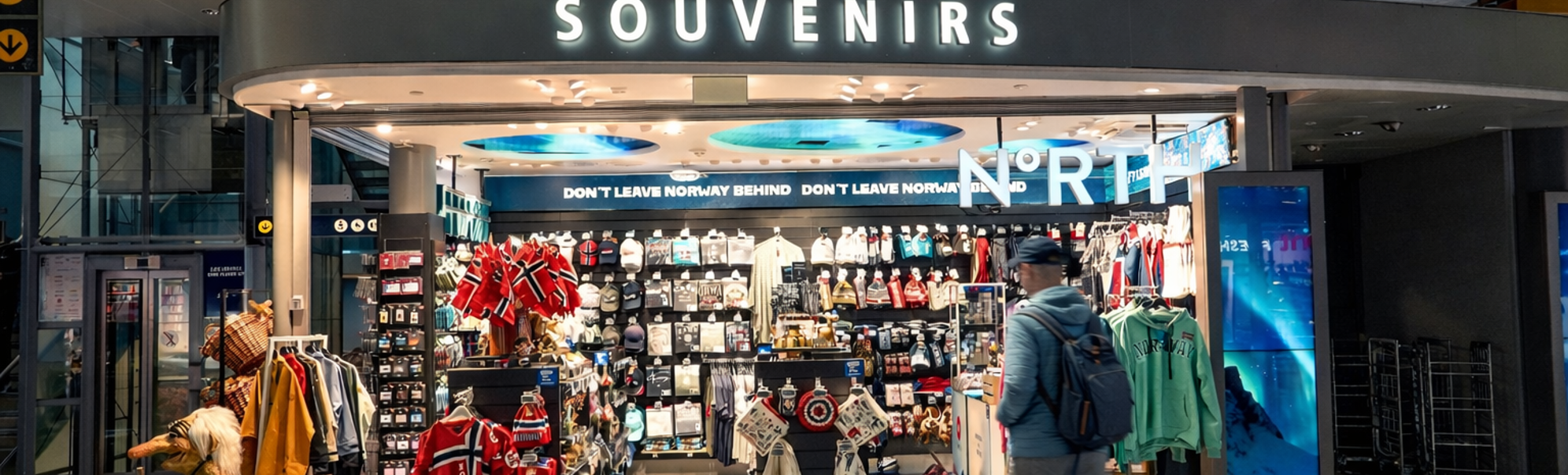 Souvenir shop in Norway featuring traditional Scandinavian apparel, flags, and assorted gifts with prominent signage for "Souvenirs" and "North