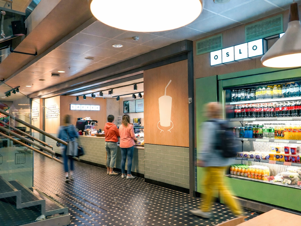 Moderne kaffebardisk med en ny meny vist på digitale skjermer, med en espressomaskin og et utvalg av kaffeforsyninger