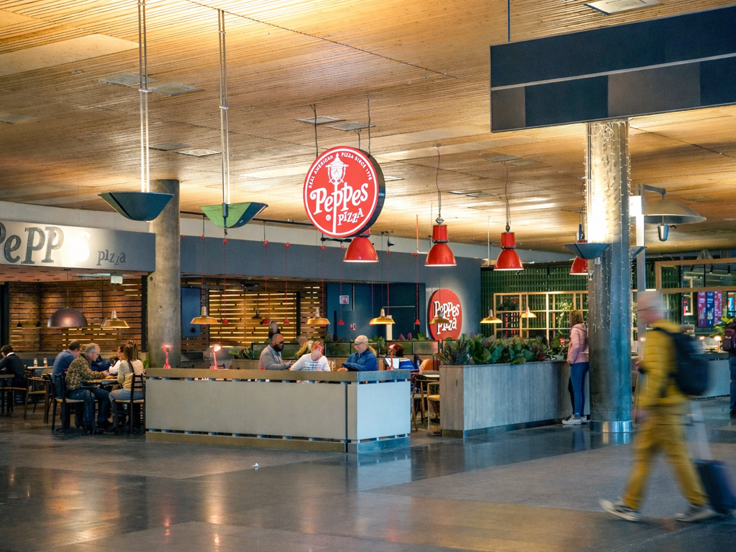 Person som skjærer en pizza toppet med ruccola og prosciutto på en hvit tallerken.