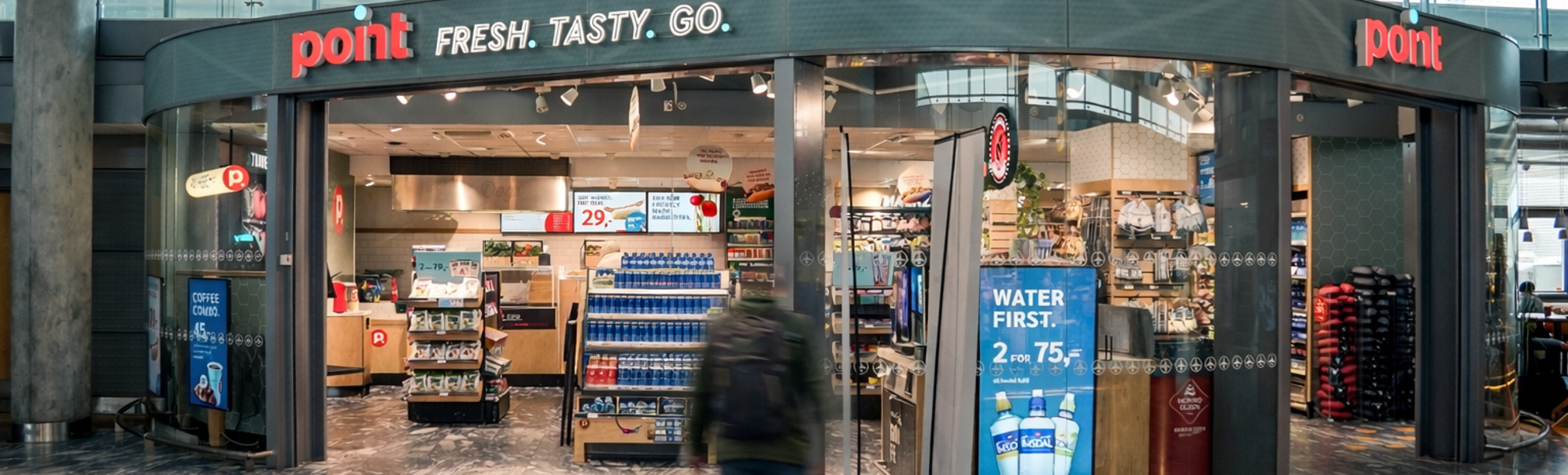 Skilt med teksten "Point Fresh Tasty Go" på ein kiosk i moderne design, inne i ein bygning