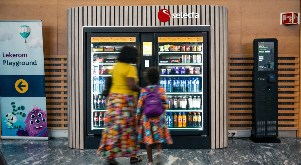 Vending machine offering a variety of snacks and candy bars, including Oreo cookies, Snickers, and Twix, with illuminated keypad