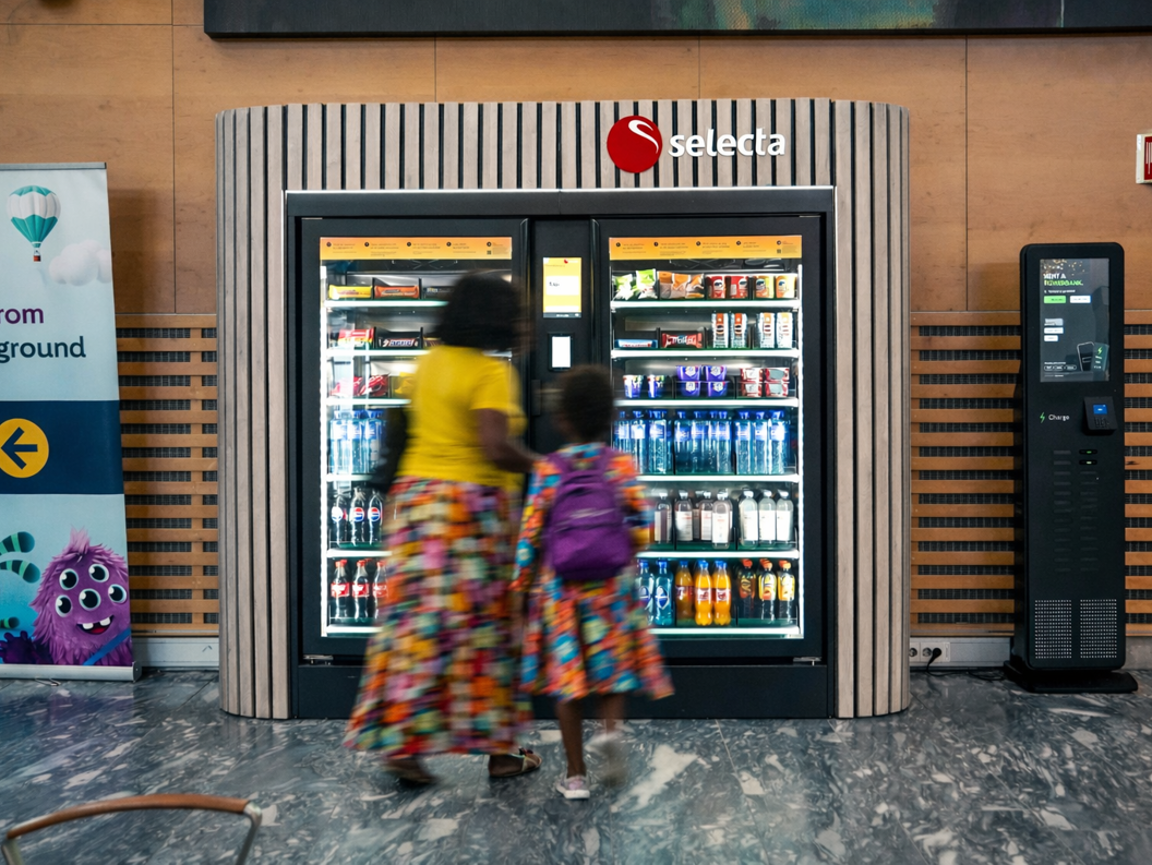Vending machine stocked with assorted snacks and candy, including chocolate bars and chips, with illuminated keypad