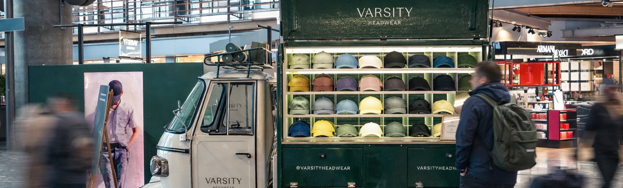 Two stylish caps, one green and one gray, are placed on stacked white concrete blocks with a dark background