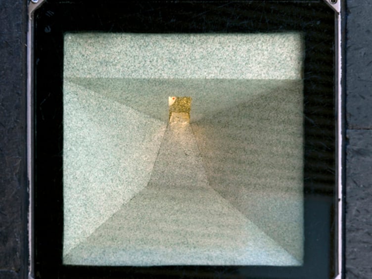 Top-down utsikt av en firkantet sjakt med lys ved bunnen, omkranset av en mørk metallramme