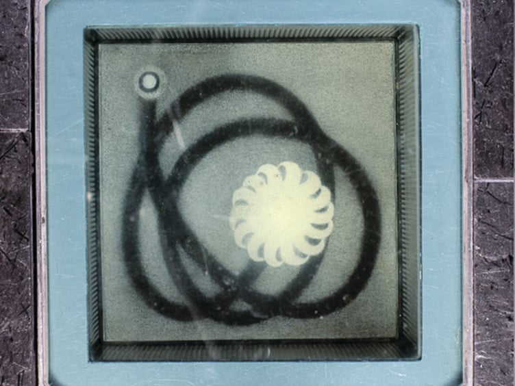 Abstrakt kunstverk bak glass med sirkulære og spiralformer i svart og hvitt