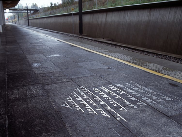 Tom jernbaneperrong med runeinskripsjon på gulvet, avbildet ved en moderne togstasjon i Norge