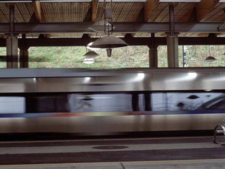 Høyhastighetstog passerer gjennom en moderne togstasjon med tredekor i taket