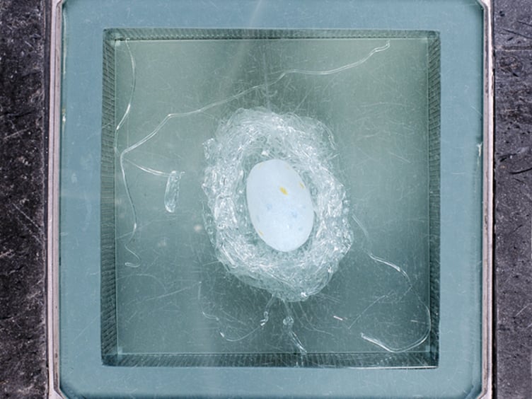 Glassgulv med tydelig sprekkdannelse og hvitt objekt, muligens et egg, i sentrum