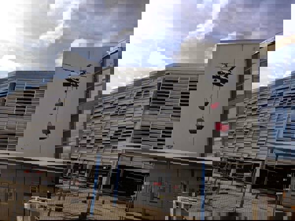 Kunstverk på Stavanger flyplass, maleri utenpå terminalbygget. To hjerter i rødt henger fra et fly