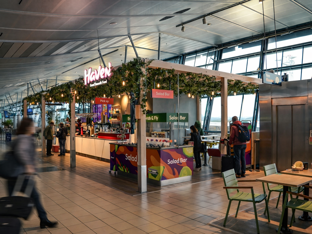 Sunn frokostbolle med skivet kiwi, bringebær, kokosflak og hakkede nøtter på en lys granittbakgrunn