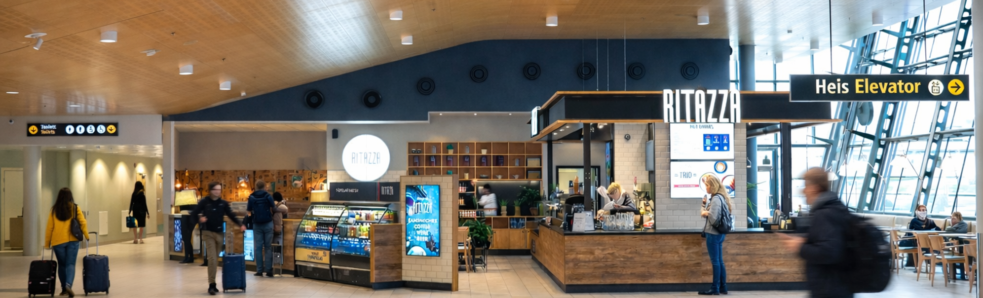 Modern airport food court with Ritazza coffee kiosk, travelers, and elevator signage inside a spacious terminal