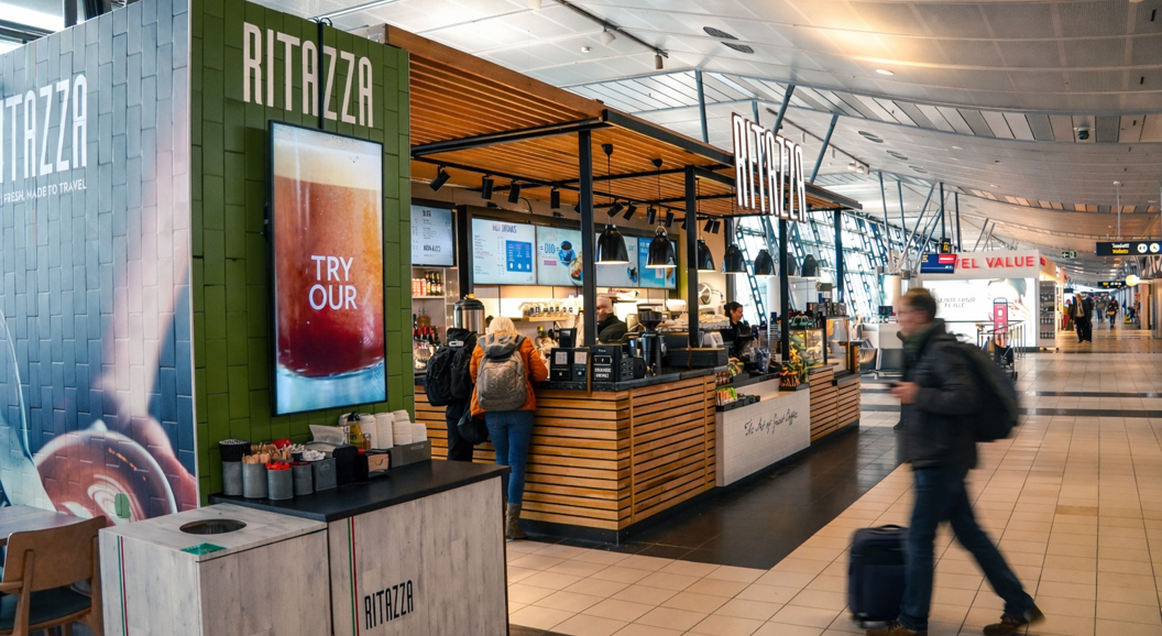 Kunder som venter ved disken i kaffebaren Caffè Ritazza, med en variert meny og Lavazza-merkevare, plassert i en flyplassterminal